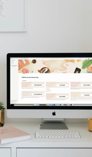 Un ordinateur Apple sur un bureau avec un écran affichant une interface de tableau de bord intitulée 'Tableaux de bord Sunny Day', entouré d'objets de décoration comme des plantes et des tasses.
