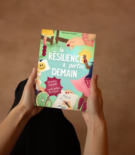 Une personne tenant un livre intitulé 'la résilience à portée, demain' sur un fond beige.