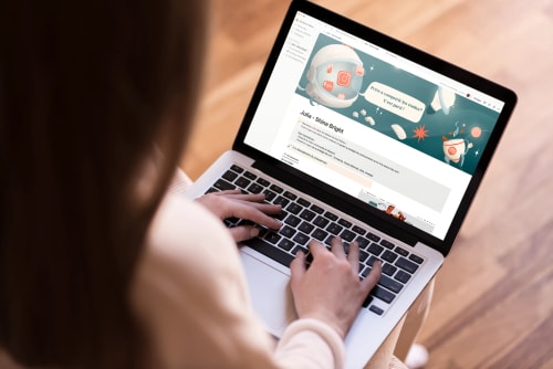 Une personne utilisant un ordinateur portable avec un site web affichant des graphiques et des éléments visuels, assise sur un sol en bois.