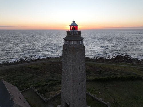 Coucher de soleil à l'arrière d'un phare au bord de la mer.
