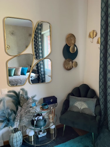 Salon de massage Abracadabra Spa, situé à Wasquehal, Nord, avec draps en velours vert, coussins décoratifs, et tableau au mur avec un motif rayonnant. Le sol est couvert d'un tapis turquoise et il y a des décorations murales dorées.