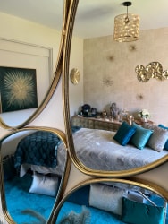 Salon de massage Abracadabra Spa, situé à Wasquehal, reflétée dans un miroir, avec des tons turquoise et or, des coussins décoratifs et des éléments de décoration murale.