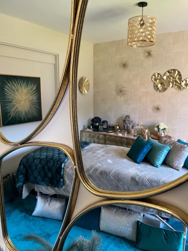 Salon de massage Abracadabra Spa, situé à Wasquehal, reflétée dans un miroir, avec des tons turquoise et or, des coussins décoratifs et des éléments de décoration murale.