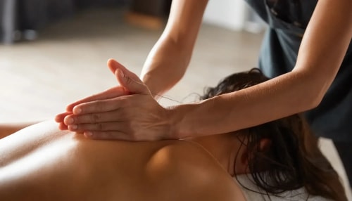 Une personne recevant un massage, avec des mains en train d'appliquer une pression sur le dos de la personne allongée.