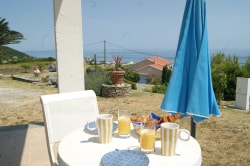 Terrasse d'une maison avec un écran bleu, une table pliante et un panier sur le dessus, et une porte-fenêtre donnant à l'intérieur.