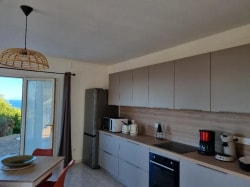 Cuisine moderne avec un réfrigérateur, un four, une cafetière, et une vue sur l'extérieur.