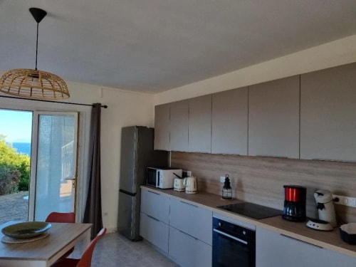 Cuisine moderne avec un réfrigérateur, un four, une cafetière, et une vue sur l'extérieur.