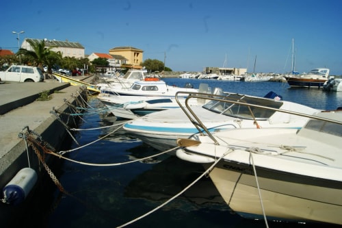 Vue d'un port avec plusieurs bateaux amarrés, le ciel est bleu et ensoleillé.