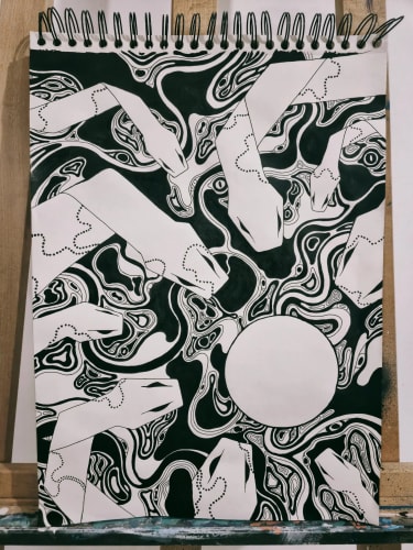 Dessin en noir et blanc représentant des serpents stylisés entrelacés dans un motif abstrait et organique, avec un cercle blanc vide au centre, sur une page de carnet à spirales posée sur un chevalet.