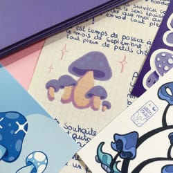 Illustration de créatures marines bleues, dont une pieuvre tachetée, un poisson et un hippocampe, sur une feuille blanche posée sur un fond vert.