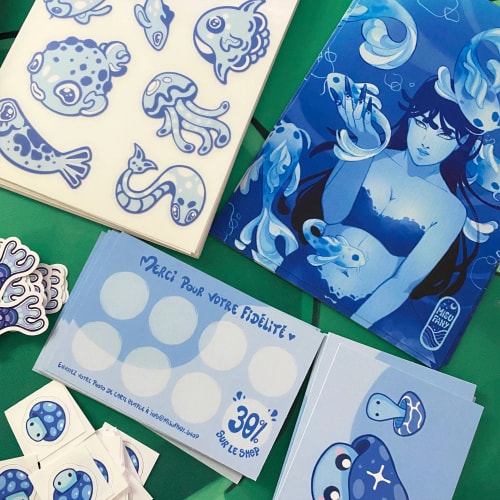 Illustration de plusieurs cartes artistiques bleues représentant des créatures marines, une sirène et des motifs océaniques, disposées sur un fond vert.