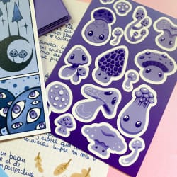 Illustration de créatures marines bleues, dont une pieuvre tachetée, un poisson et un hippocampe, sur une feuille blanche posée sur un fond vert.