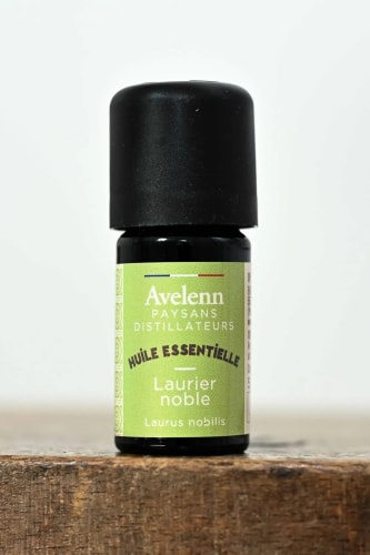 Flacon d'huile essentielle de Laurier noble de la marque Avelenn, posé sur une surface en bois.