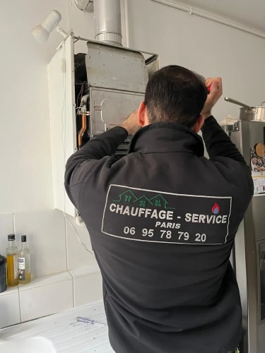 Une personne de dos, vêtue d'une veste noire avec une inscription, marche sur une allée pavée dans un jardin enneigé à Paris.