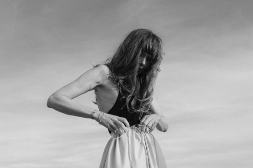 Christine Mercadier portant le jupon Gris perle de la marque avec un ciel marin en fond