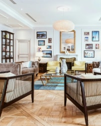 Intérieur d'un salon élégant avec des canapés, une table basse en verre et des murs ornés de cadres photo, ainsi qu'une cheminée décorative, pour représenter les prestations de shopping déco proposées par Inès Home Design