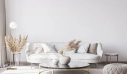 Un salon moderne avec un canapé blanc, des coussins beige, une table basse noire, des arrangements floraux et un lampadaire, pour représenter le salon Feng Shui