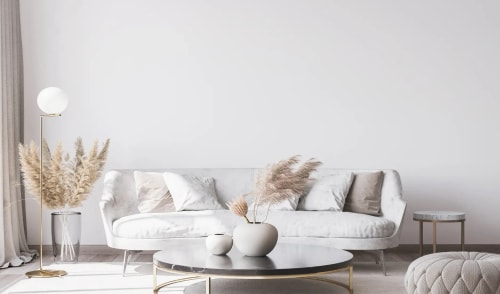 Un salon moderne avec un canapé blanc, des coussins beige, une table basse noire, des arrangements floraux et un lampadaire, pour représenter le salon Feng Shui