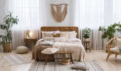Chambre à coucher lumineuse et élégante avec un lit en bois, des coussins et des couvertures, des plantes d'intérieur, un tapis, des rideaux transparents et une décoration murale en macramé, pour illustrer l'art de l'harmonie et du Feng Shui