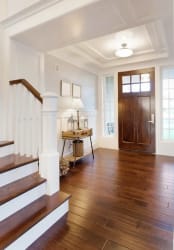 Intérieur d'une entrée avec des escaliers, un sol en bois, une lampe suspendue, une table décorative et une porte en bois