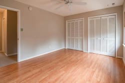 Une pièce avec un sol en bois, un ventilateur de plafond, des murs de couleur claire et des portes à rideaux, pour illustrer les services de déco par pièce