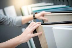 Une main touchant des échantillons de matériaux pour illustrer les services de shopping de décoration d'intérieur qu'Inès Home Design peut effectuer pour vous et votre intérieur