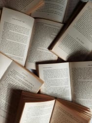 Des pages de livres ouvertes en désordre, montrant du texte imprimé, avec quelques chapitres visibles, pour illustrer les services aux auteurs proposés par l'agence éditoriale Les Belles Personnes