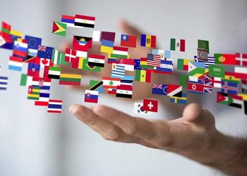 Une main tenant des mini-drapeaux du monde entier flottant autour, représentant la diversité des pays, pour illustrer l'accompagnement sur le potentiel international par Pro Mundi Conseil
