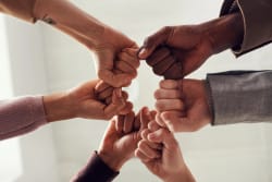 Groupe de mains s'unissant, avec des poings serrés, représentant la collaboration et l'unité.