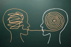 Deux silhouettes humaines, l'une avec des lignes en désordre représentant le cerveau, l'autre avec un motif en spirale, se faisant face et partageant une ligne orange entre leurs bouches.