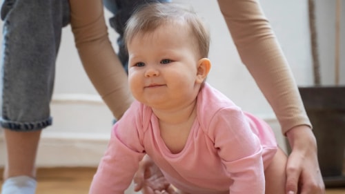 Une femme enceinte portant un débardeur orange tient un bol rempli de salade de fruits frais devant son ventre.