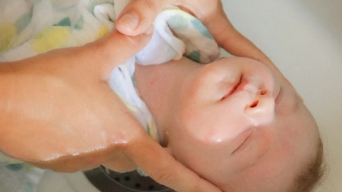 Une praticienne aux cheveux blonds, en tenue bleue, effectue une séance de soin énergétique ou de massage sur une personne allongée sur le dos, posant ses mains sur le haut du ventre de celle-ci.