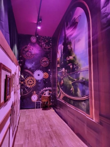 Couloir décoré avec des illustrations futuristes, incluant des horloges anciennes, des engrenages mécaniques et une grande fenêtre peinte montrant un paysage fantastique avec une tour et des éléments flottants, éclairé par une lumière violette.