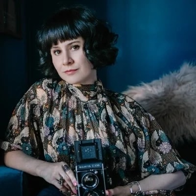 Portrait photo de Rachel Calvo, tenant un appareil photo ancien.