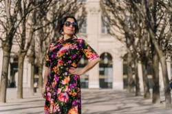Photo de Frances Vieras Blanc, CEO d'Eat the Cake Studio, posant au soleil dans une robe fleurie et portant des lunettes de soleil.