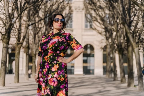 Photo de Frances Vieras Blanc, CEO d'Eat the Cake Studio, posant au soleil dans une robe fleurie et portant des lunettes de soleil.