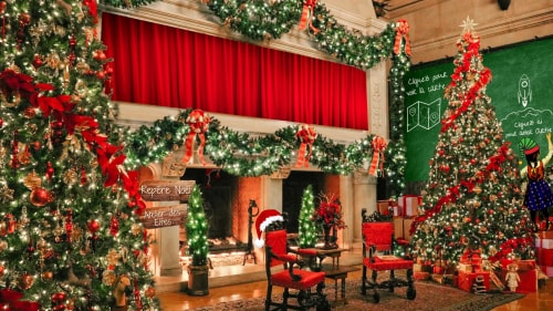 Salon décoré pour Noël avec un grand sapin illuminé, des guirlandes vertes et rouges, des cadeaux, deux fauteuils rouges, une cheminée allumée et une petite fille habillée en lutin écrivant sur un tableau vert.