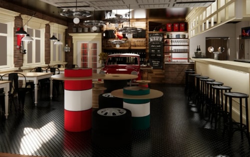 Intérieur d'un café au style vintage avec des tables fabriquées à partir de pneus peints en rouge, blanc et vert, un bar à droite avec des tabourets noirs, des tables et chaises en bois à gauche, et une vieille voiture rouge placée à l'arrière sous un panneau de menu noir suspendu au mur en briques.