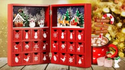 image montrant plusieurs cadeaux et objets de fête sur une table devant une fenêtre, comprenant des biscuits de Noël, une bouteille de champagne, un serre-tête avec des bois de renne, un bonbon canne, une bougie parfumée, un jeu de pâte à modeler, une maison en pain d'épice, et un sac cadeau avec motif de rennes rouges