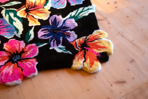 Une peinture aux couleurs vives représentant des fleurs tropicales roses, rouges et orange contrastant avec un feuillage vert sur un fond noir.
