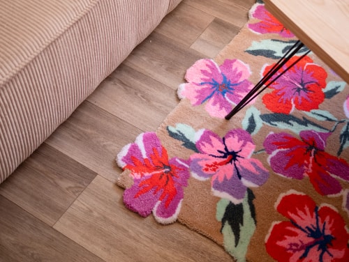 Une peinture aux couleurs vives représentant des fleurs tropicales roses, rouges et orange contrastant avec un feuillage vert sur un fond noir.