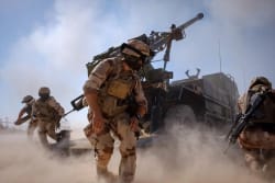 Des soldats sur un terrain poussiéreux sont en train de tirer à l'aide du système d'artillerie CAESAR