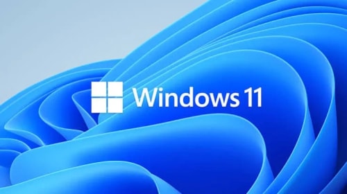 Logo Windows 11 blanc au centre sur un fond abstrait bleu composé de formes ondulées.
