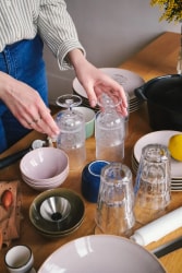 Fanny Taudou de Taudou List rangeant et organisant de la vaisselle sur une table de salle à manger