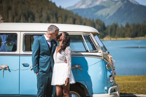 Un homme avec une barbe et un chapeau travaille sur un fauteuil en bois dans un atelier encombré d'outils et de matériaux. La lumière naturelle entre par la fenêtre, créant une ambiance chaleureuse et artisanale.