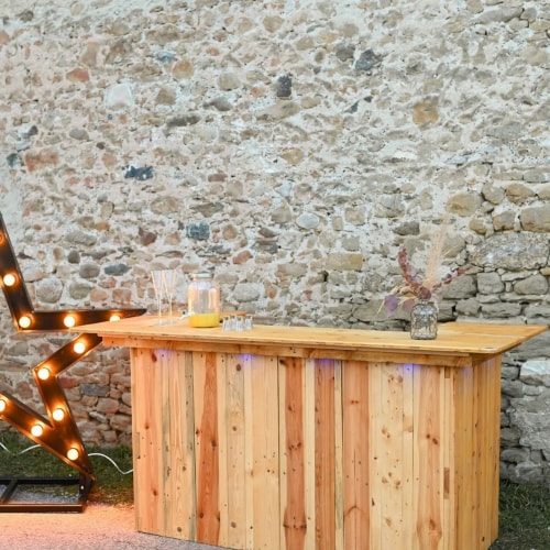 Un bar en bois clair avec un fond en pierre et une décoration lumineuse en forme d'étoile.