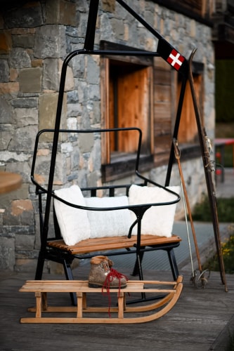 Un bar moderne avec un comptoir sombre, des murs en béton et un éclairage doux. Au centre, une table ronde en bois avec un seau à glace contenant une bouteille et deux verres de vin. À l'arrière-plan, une sélection de boissons est affichée sur un mur.