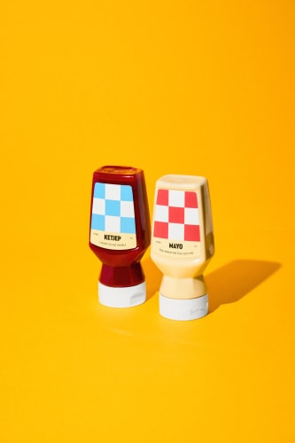 Deux bouteilles de condiments sur un fond jaune : un ketchup rouge avec une étiquette bleue et une mayonnaise blanche avec une étiquette beige.