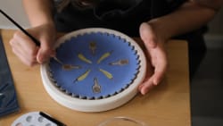 Quatre personnes discutent autour d’une table dressée, dans une pièce aux murs en pierre, tandis qu’une serveuse présente un plat.