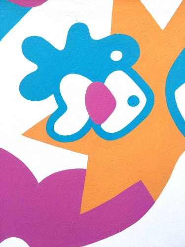 Gros plan sur une peinture murale abstraite aux formes organiques colorées : étoile orange, silhouettes bleu vif, taches blanches et roses sur fond blanc. Style ludique et dynamique.